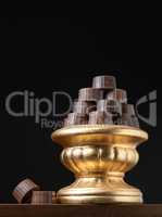 Stack of Fine Chocolates On Golden Pillar Dish With Dark Backgro