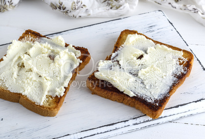 toasted bread with soft curd on a white wooden board