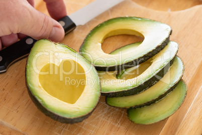 Male Hand Prepares Fresh Cut Avocado With Heart Shaped Pit Area