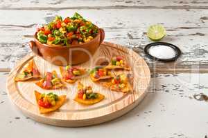 Nachos chips and vegetables in an earthenware bowl and tequila