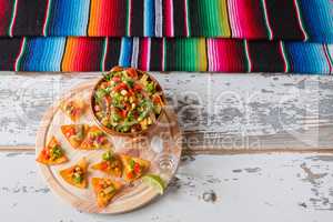 Nachos chips and vegetables in an earthenware bowl tequila lime