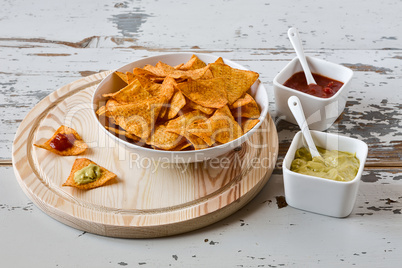 Nachos chips with sauce on a chopping board