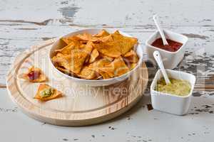 Nachos chips with sauce on a chopping board