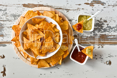 Nachos in a white bowl and sauces