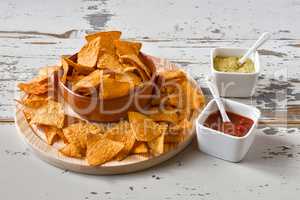 Nachos in an earthenware bowl and sauces