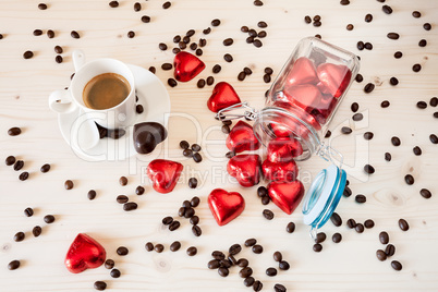 Red chocolate hearts in a glass jar and a cup of espresso coffee