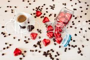 Red chocolate hearts in a glass jar and a cup of espresso coffee