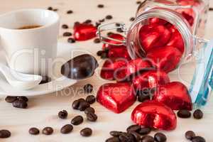 Red chocolate hearts in a glass jar and an espresso coffee