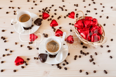 Red chocolate hearts in a small basket and two cups of coffee