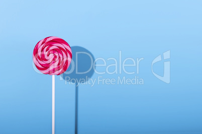 Pink Lolipop candy with shadow on pastel blue background