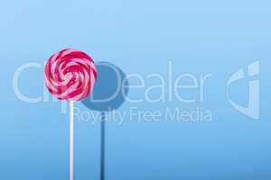 Pink Lolipop candy with shadow on pastel blue background