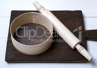 brown wooden kitchen cutting board, rolling pin and sieve