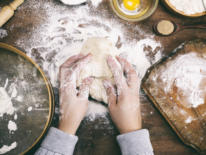 two female hands knead a dough of white wheat flour
