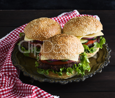 three burgers with a meat chop, vegetables and cheese