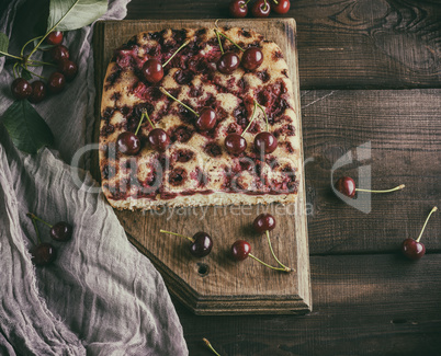 baked cake with cherries on a brown wooden board