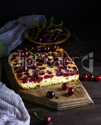 baked cake with cherries on a brown wooden board