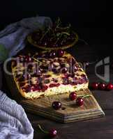 baked cake with cherries on a brown wooden board