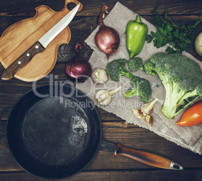 empty round black cast-iron frying pan and fresh vegetables