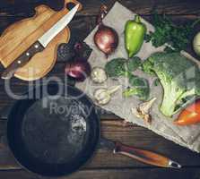 empty round black cast-iron frying pan and fresh vegetables