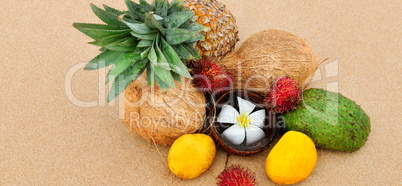 Set of tropical fruits on a sandy beach. Wide photo.