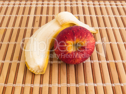 Peeled banana and apple on wooden table