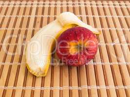 Peeled banana and apple on wooden table
