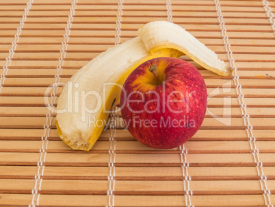 Red apple and peeled banana close up view.