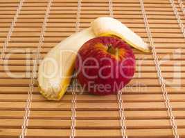 Delicious red apple and peeled banana on wooden slats.