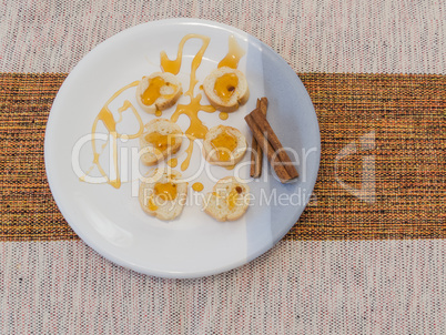 Small torrads accompanied by honey and cinnamon on white plate.