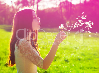woman blowing on a dandelion