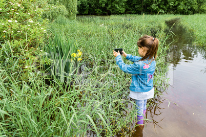 Girl stands in the water and takes pictures