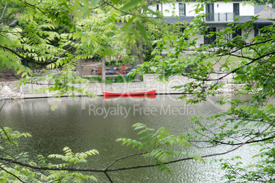 Red canoe on a leash near a house on the river