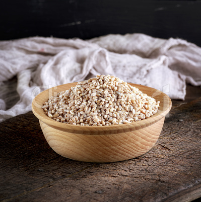 wheat grain in a wooden bowl on a brown table