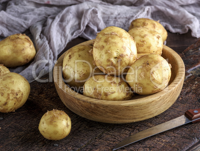 potatoes in the peel lay in a wooden bowl on a brown table