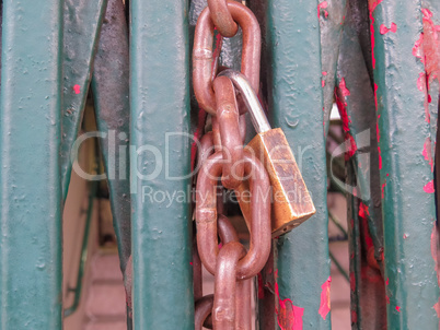 Rusty padlock and chain, closing grille gate.