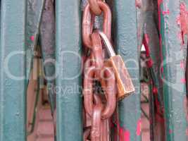 Rusty padlock and chain, closing grille gate.