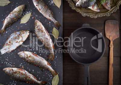 river fish on a black board and a black cast-iron frying pan