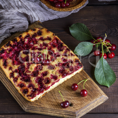 baked cake with cherries on a brown wooden board