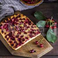 baked cake with cherries on a brown wooden board