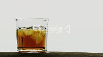 Ice cubes dropped in glass of orange ice tea,