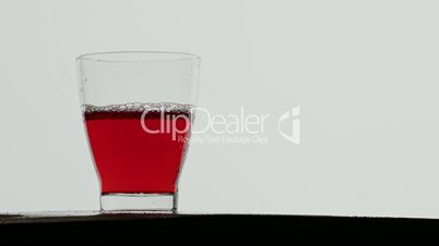 Ice cubes dropped in glass of red juice