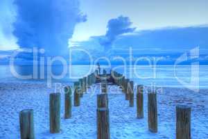 Fisherman stands on an old pier at the ocean on Naples Beach