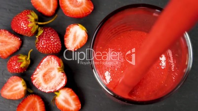 Strawberry smoothie flowing in glass
