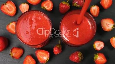 Fresh strawberry smoothie flowing in glasses ready to drink