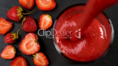 Fresh strawberry smoothie flowing in glass
