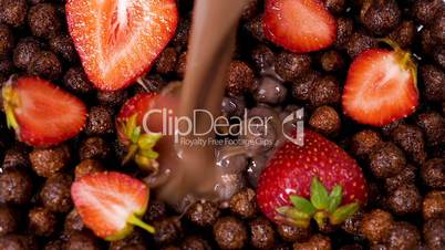 Milk with chocolate flowing on cocoa cereals with strawberries