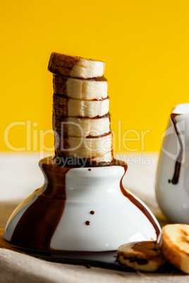 Banana slices in a little bowl with liquid chocolate.