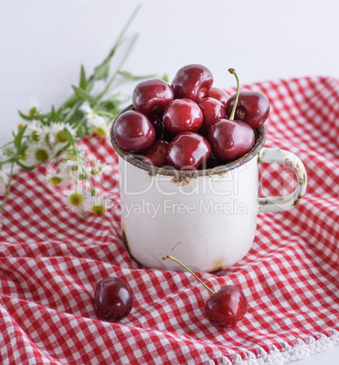 white iron mug with ripe berries of red cherry