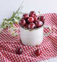 white iron mug with ripe berries of red cherry