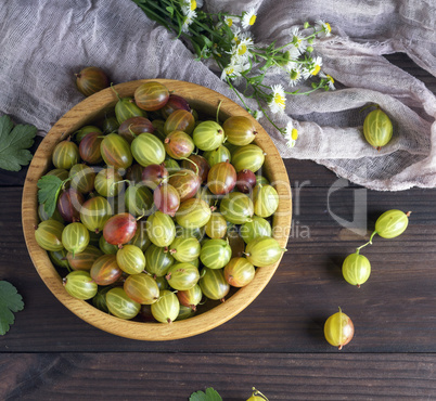 round wooden bowl with green gooseberries